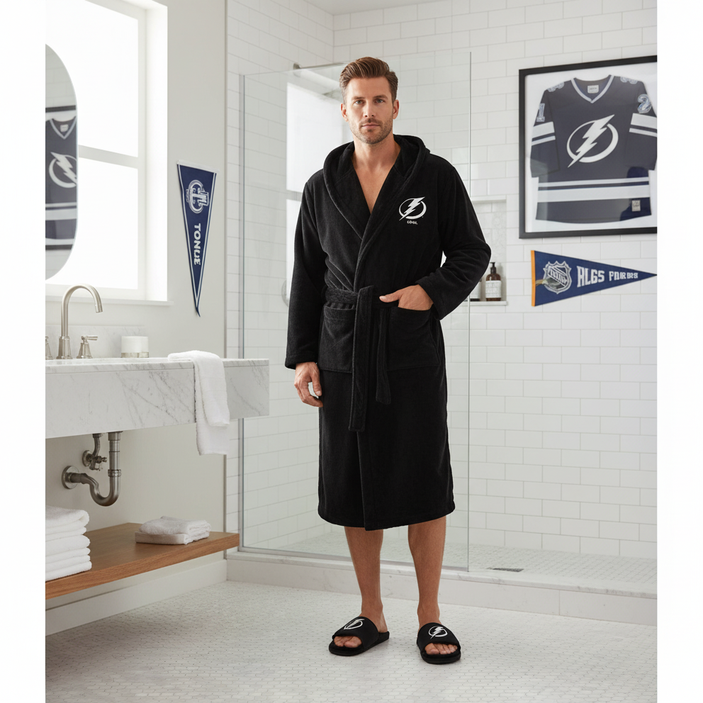 A hooded robe with a logo on the hood and a pair of black fuzzy slippers with a logo on the strap, both laid out on a white background.