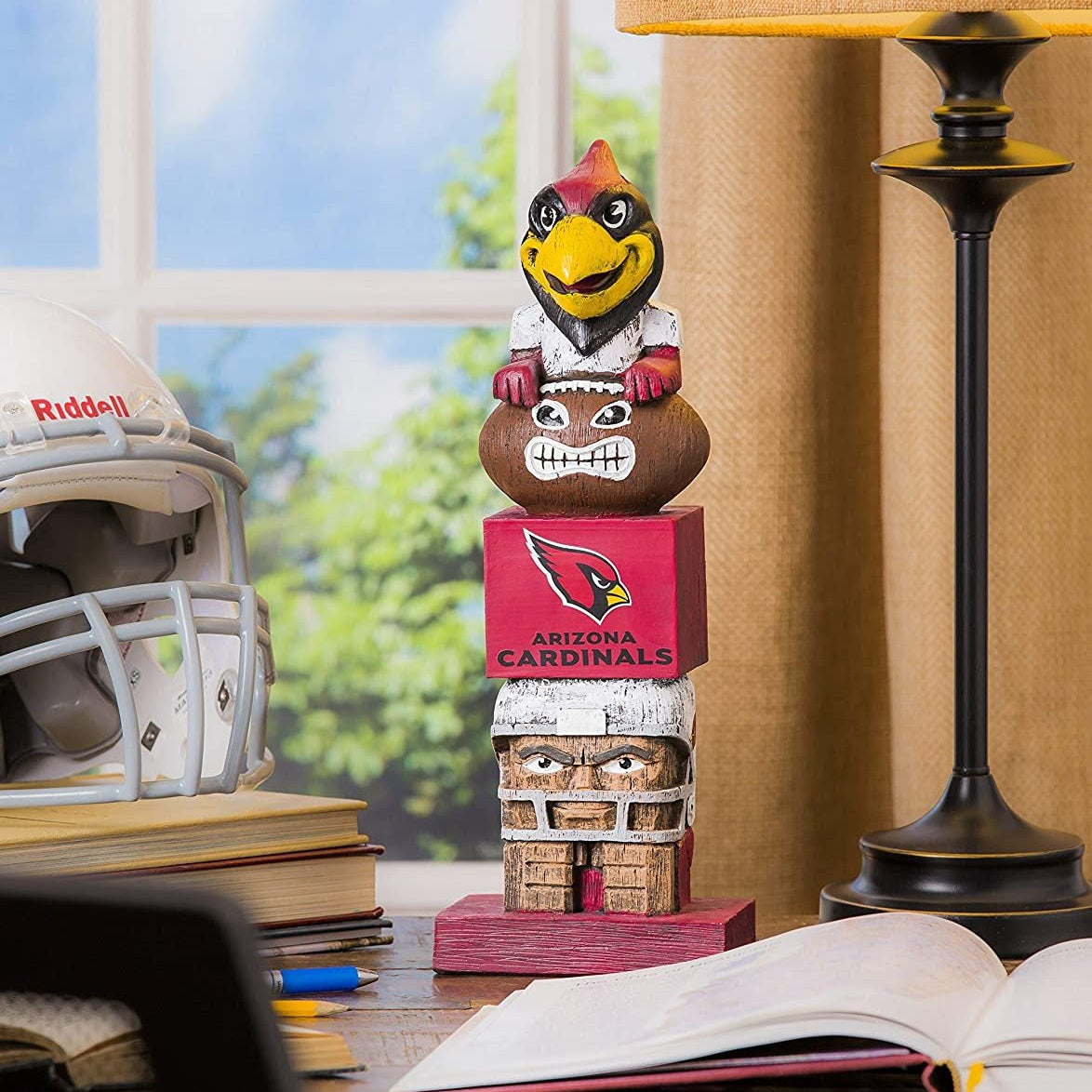 Arizona Cardinals totem figurine on a desk with books and a helmet in the background