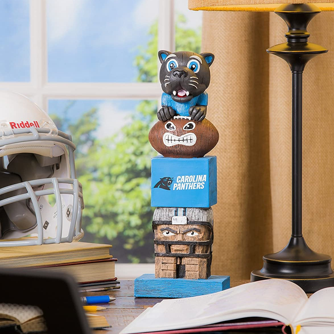 Carolina Panthers totem figurine on a desk with books and a helmet in the background