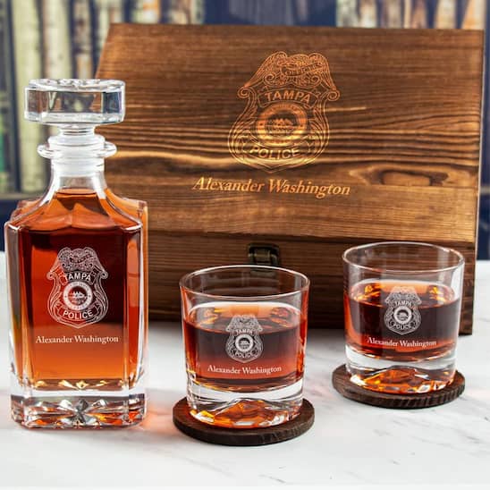 Whiskey decanter and glasses with 'Tampa Police' branding on a wooden box background.
