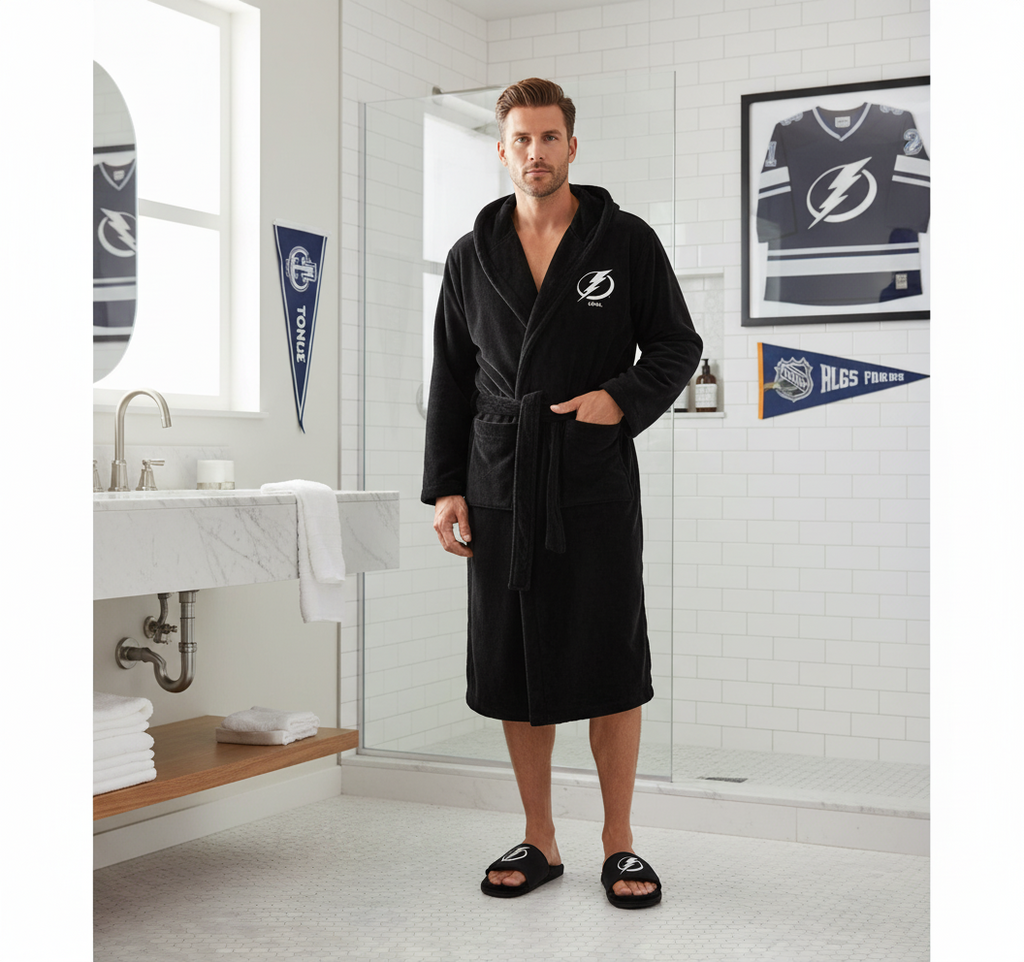 A hooded robe with a logo on the hood and a pair of black fuzzy slippers with a logo on the strap, both laid out on a white background.