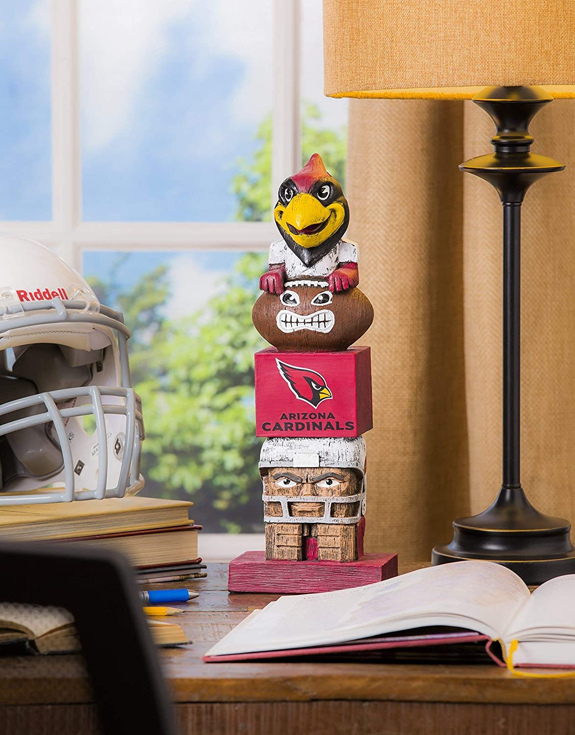 Arizona Cardinals totem figurine on a desk with books and a helmet in the background