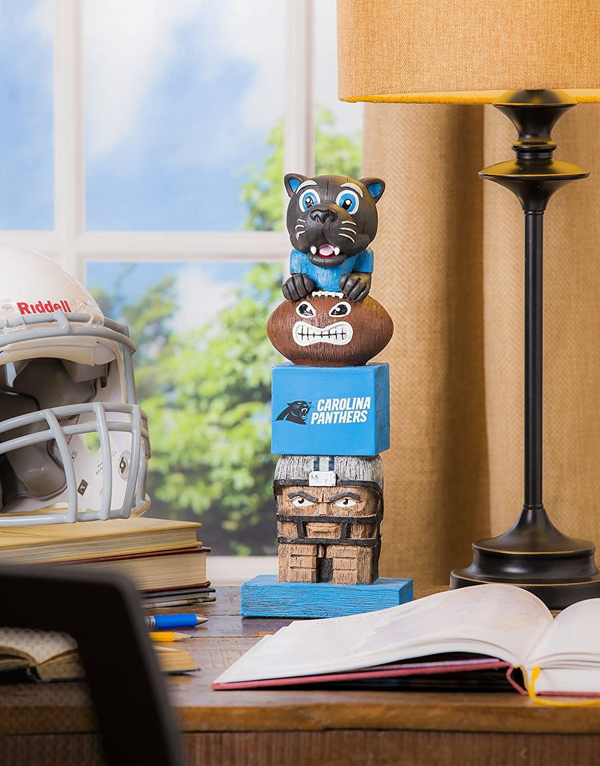 Carolina Panthers totem figurine on a desk with books and a helmet in the background